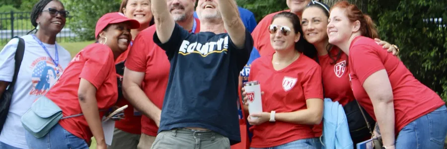 Groups of PFT members in red tshirts take a selfie with a white man in a blue shirt